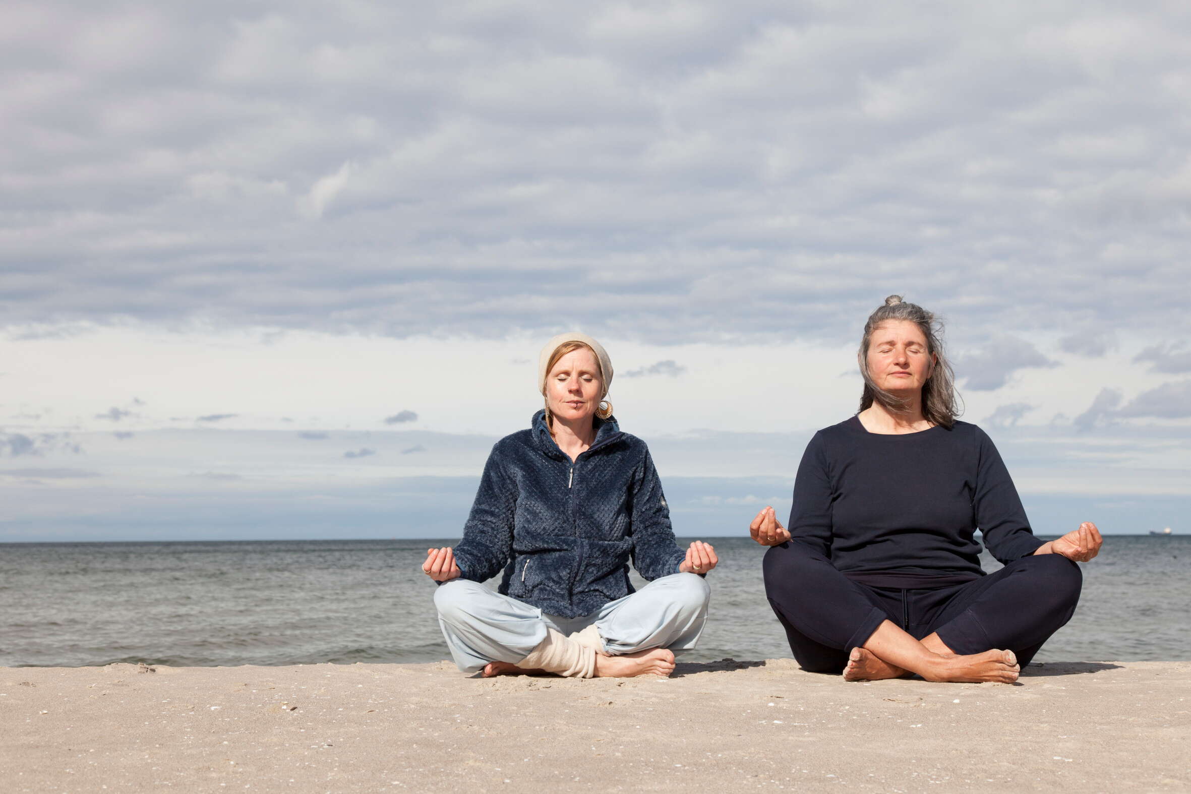 Anne Rosinski und Teilnehmerin am Strand praktizieren eine Atemtechnik